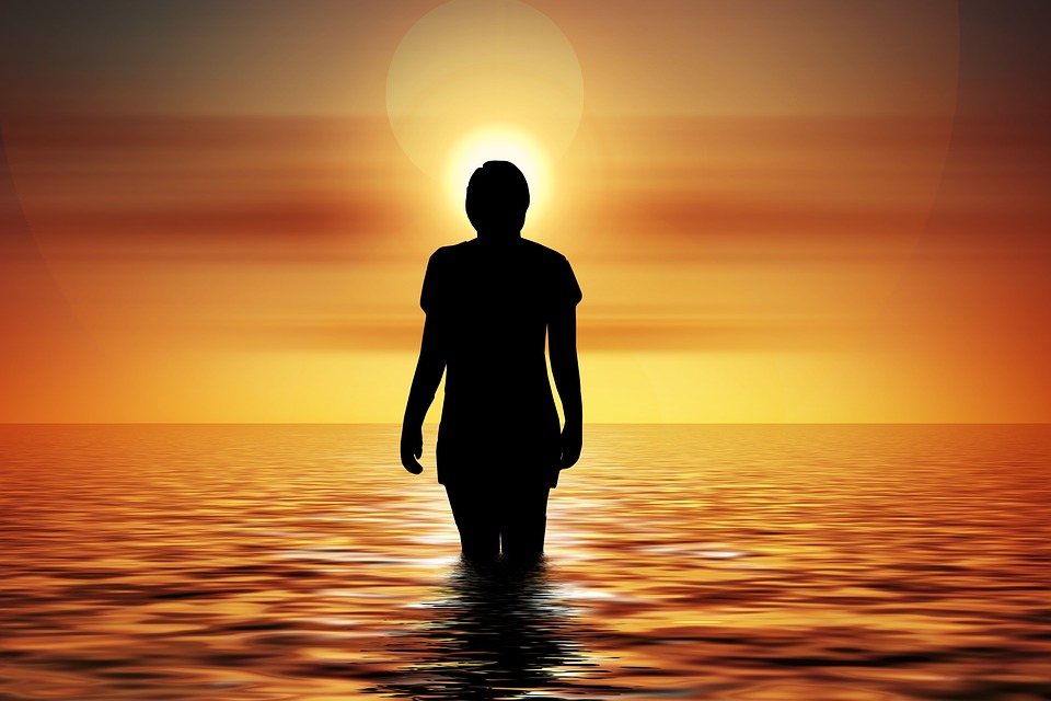 Person walking into sunset ocean