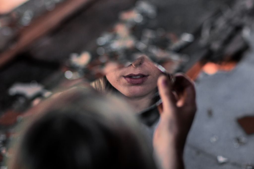 Girl looking into a shattered mirror, fearing rejection