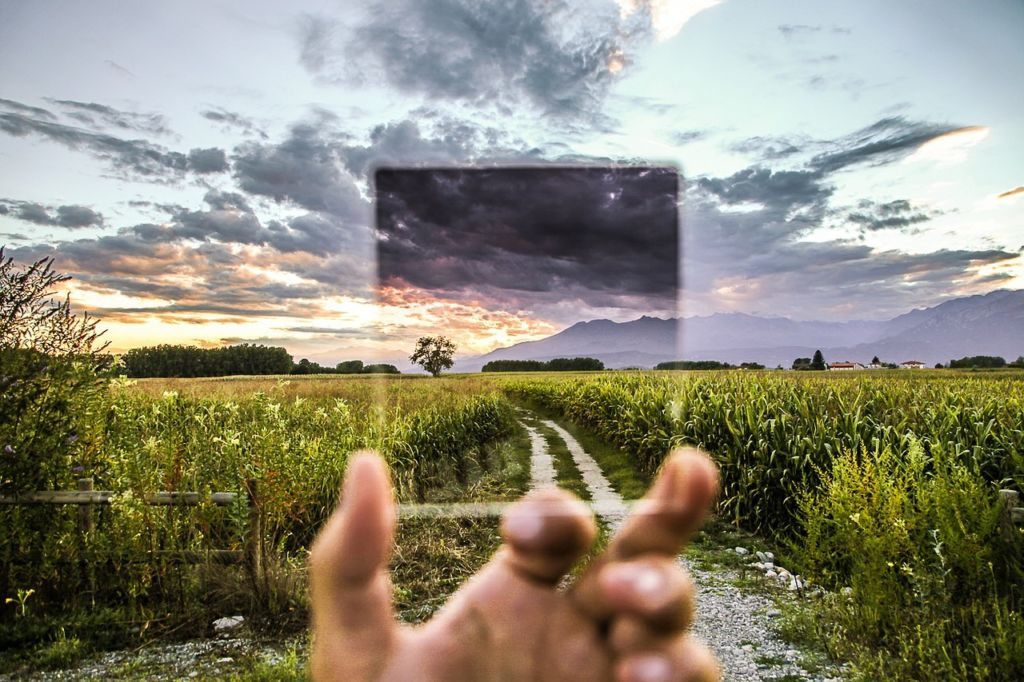 How we filter our view of our world, person holding up filter to landscape