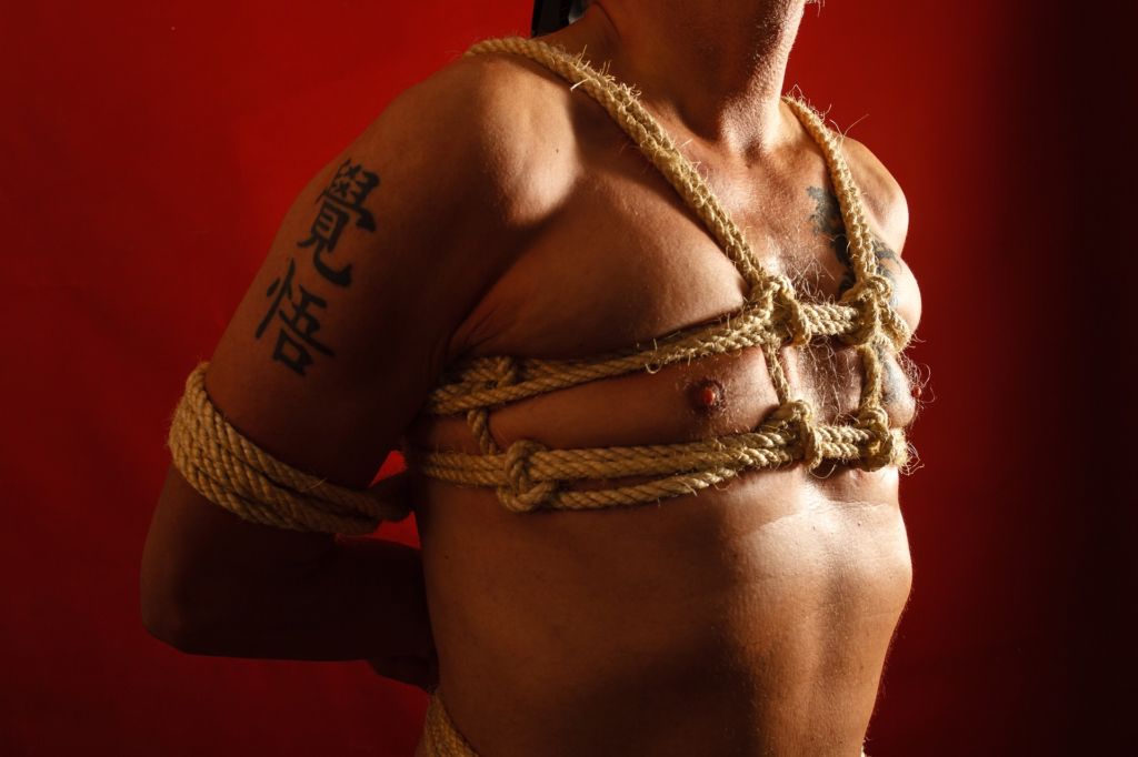 Man bound with rope harness